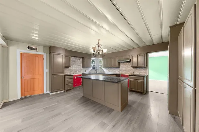 a kitchen with stainless steel appliances granite countertop a sink dishwasher a refrigerator cabinets and wooden floor