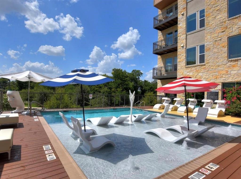 1900 Barton Springs Road, Unit 5009 Austin, TX 78704 - Photo 26 of 35 An inviting pool area with in-water lounging and ample poolside seating, all set against a contemporary building.