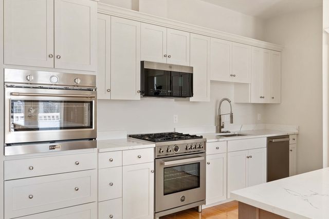 a kitchen with granite countertop white cabinets and stainless steel appliances