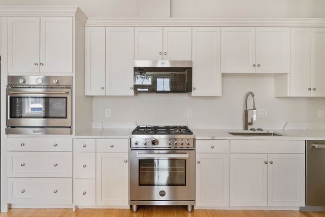 a kitchen with granite countertop white cabinets and stainless steel appliances