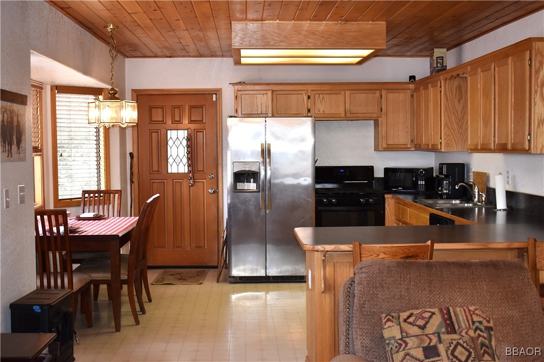 442 Inyo Avenue Sugarloaf, CA 92386 - Photo 14 of 36 a kitchen with stainless steel appliances granite countertop a refrigerator a stove and a sink with wooden floor