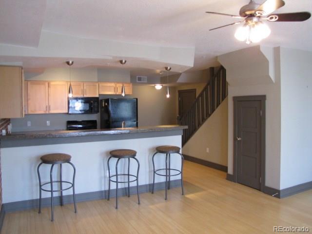 232 Broadway, Unit 2 Denver, CO 80203 - Photo 5 of 12 a kitchen with stainless steel appliances granite countertop a table chairs in it and wooden floors