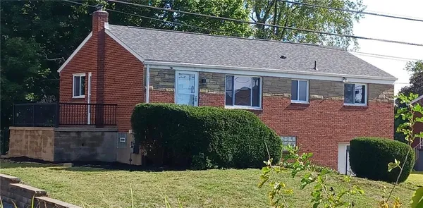 a view of a house with brick walls and a yard with plants
