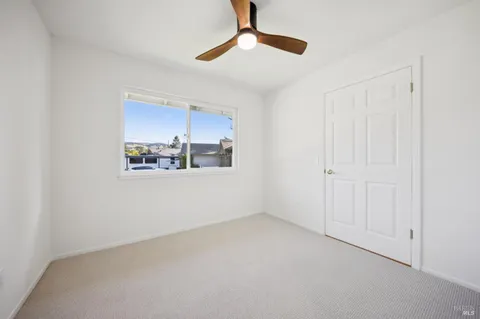 an empty room with wooden floor closet and windows