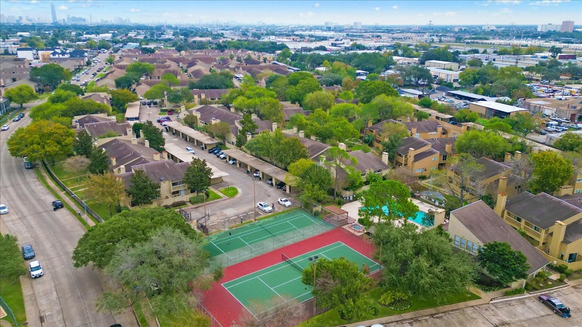 3502 Ocee Street, Unit 3502 Houston, TX 77063 - Photo 26 of 28 This aerial photo showcases a well-maintained residential community with tree-lined streets. It features a tennis court, a swimming pool, and ample parking. The neighborhood appears spacious and offers a suburban feel with convenient access to nearby amenities.