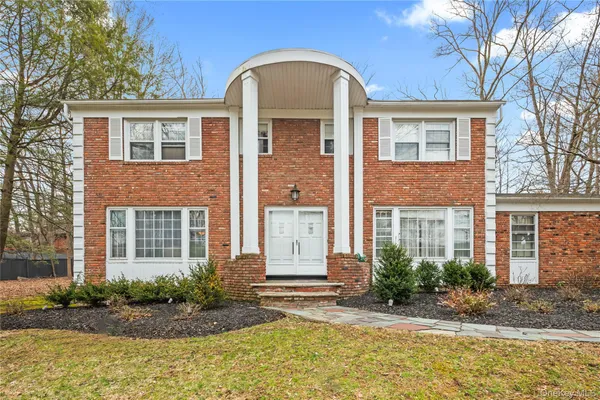 a view of a brick house with plants and large tree