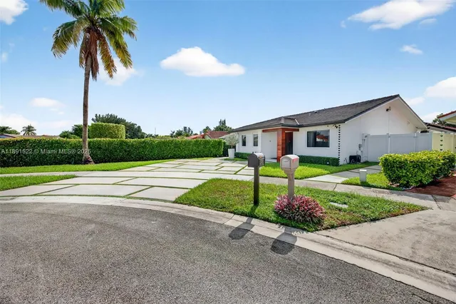 a view of a house with a yard and palm trees