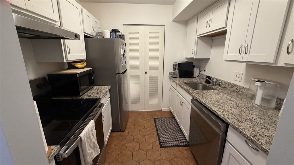 a kitchen with stainless steel appliances granite countertop a refrigerator a stove and a sink