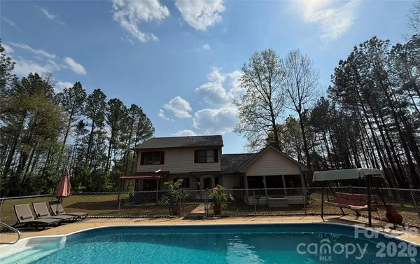 a view of swimming pool with outdoor seating and trees in the background