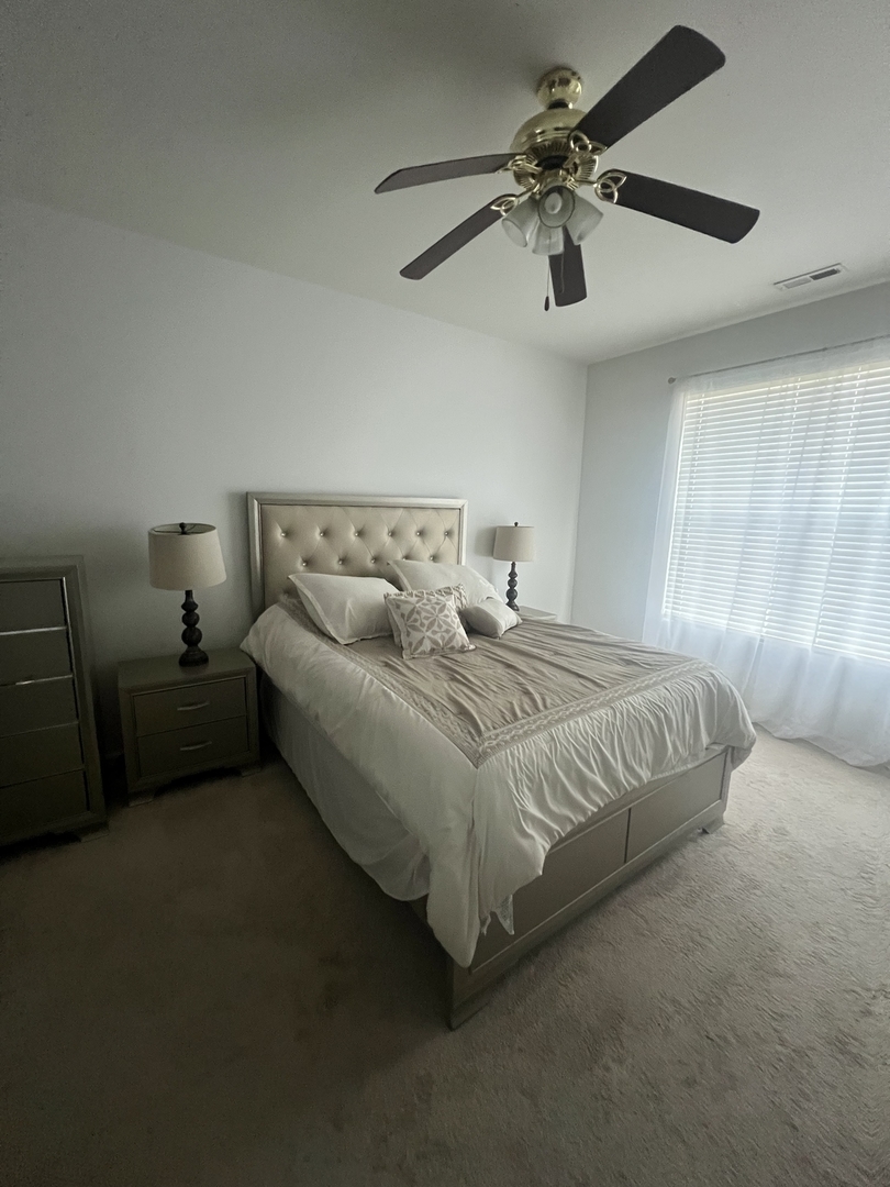 10205 Mulberry Lane, Unit J Bridgeview, IL 60455 - Photo 5 of 12 a spacious bedroom with a bed and a chandelier
