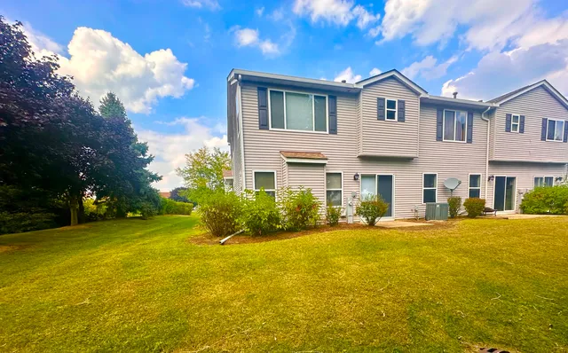 a front view of house with yard and trees in the background