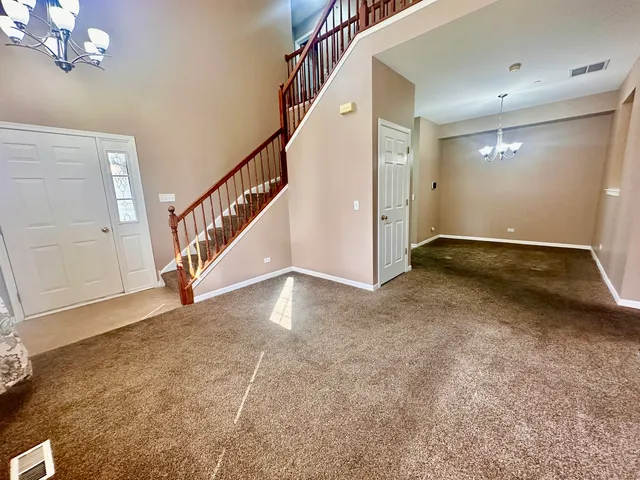 a view of an empty room with stairs and a chandelier fan
