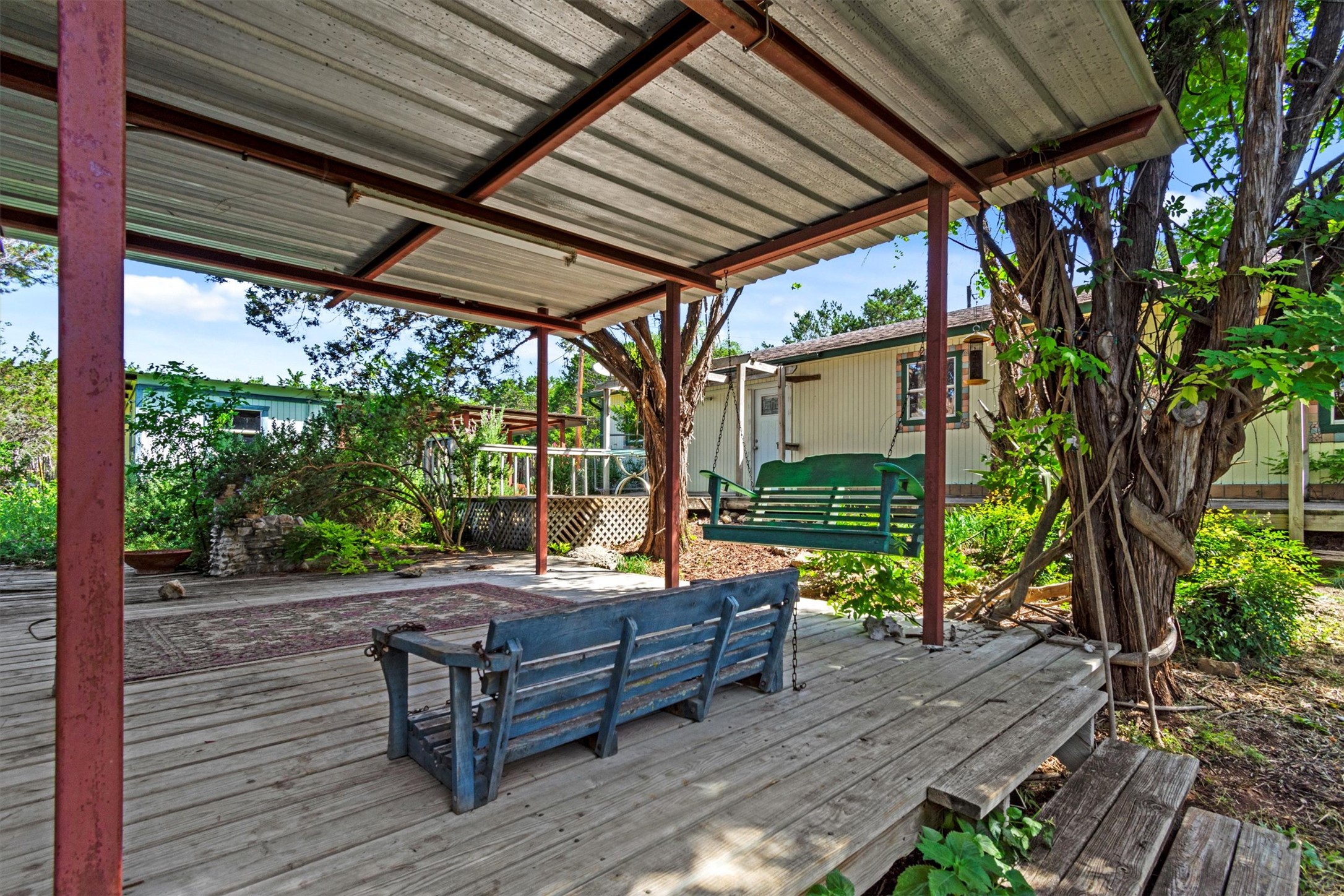 6 El Sol Road Wimberley, TX 78676 - Photo 15 of 20 Relax on the wooden porch, complete with a porch swing, offering a serene outdoor retreat.