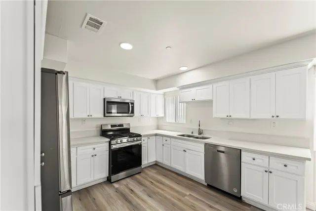 a kitchen with granite countertop a sink cabinets and stainless steel appliances