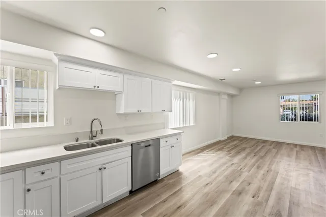 a kitchen with a sink cabinets wooden floor and a window