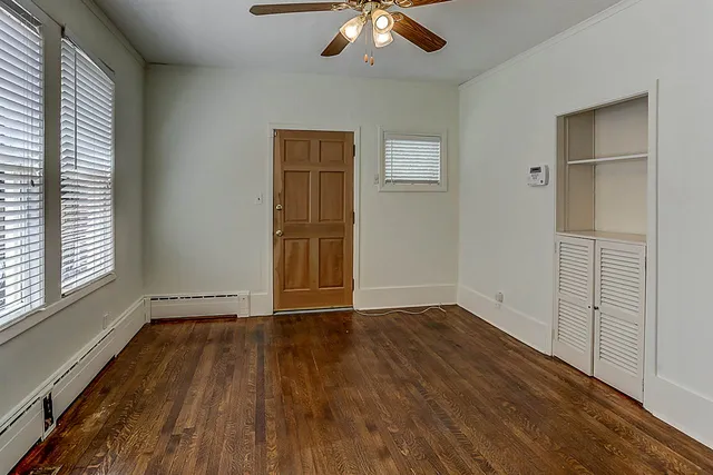 a view of an empty room with wooden floor and a window