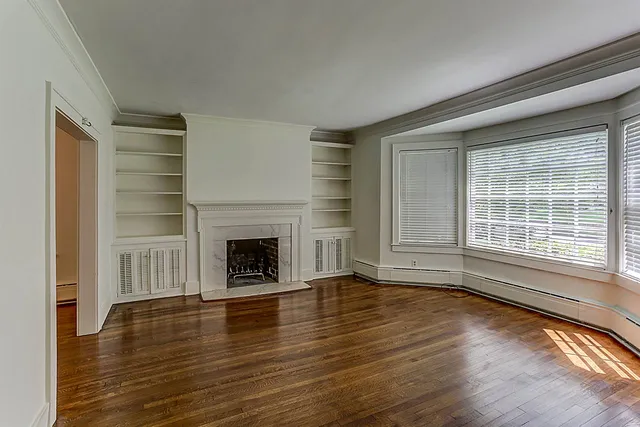 a view of a livingroom with wooden floor a fireplace and windows