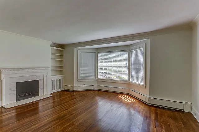 an empty room with wooden floor and fireplace