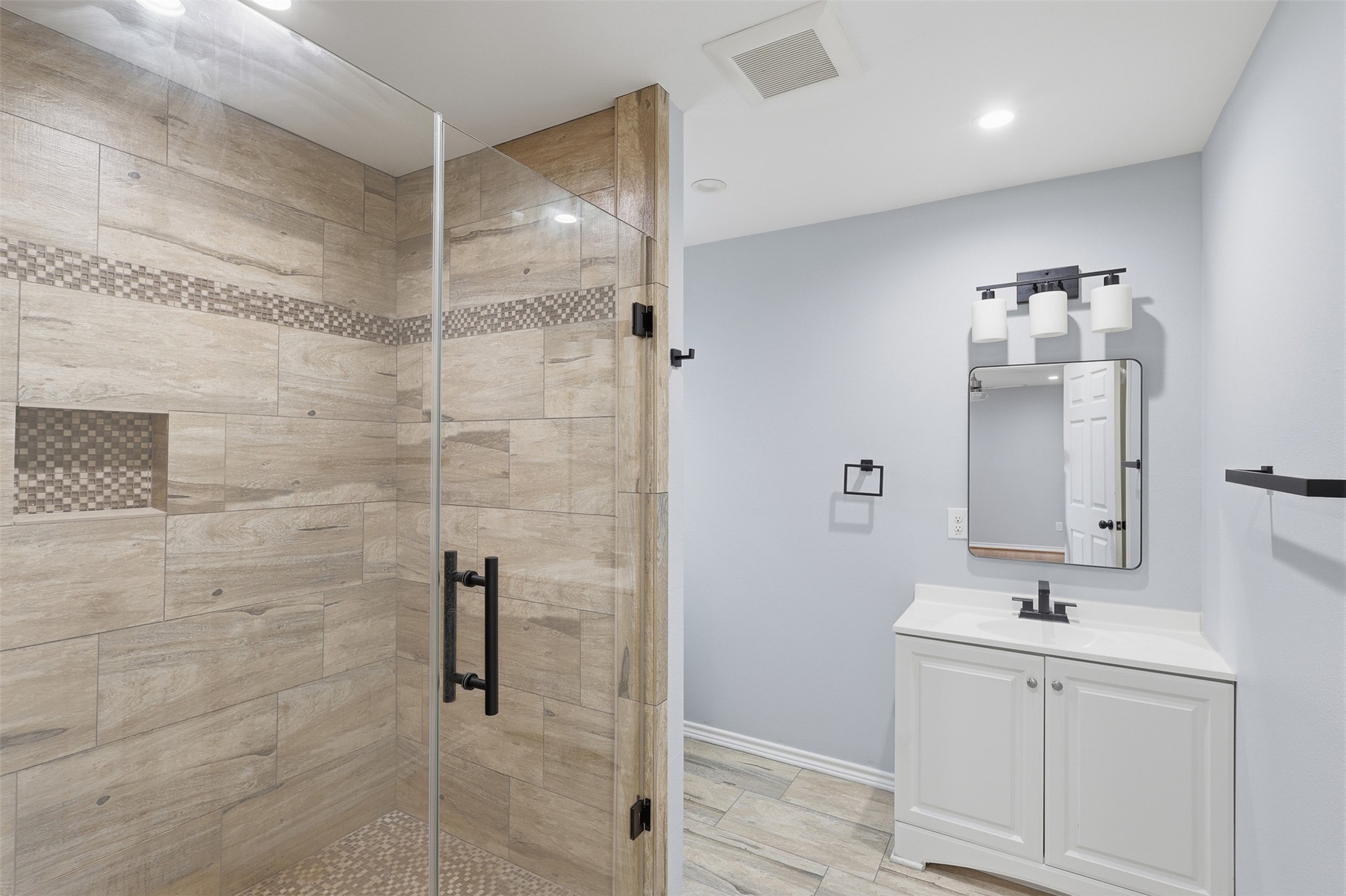 4926 Edfield Street Houston, TX 77033 - Photo 9 of 30 Stylish bathroom featuring a spacious walk-in shower with modern tile work and a sleek vanity with contemporary lighting.