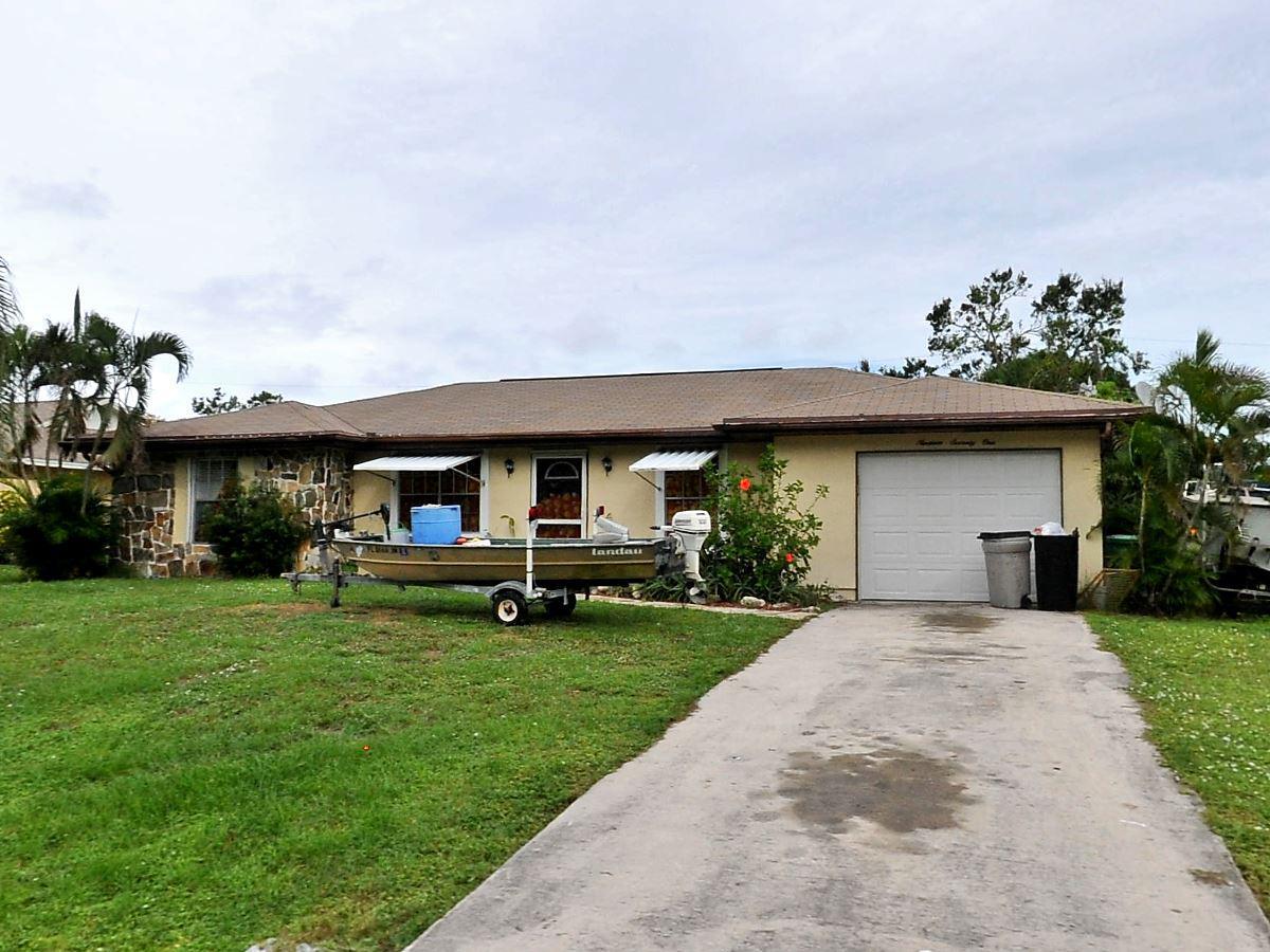 1971 Southeast Manth Lane Port St. Lucie, FL 34983 - Photo 1 of 1 a front view of a house with a garden and trees
