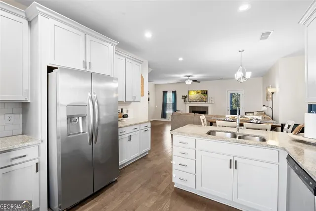a kitchen with stainless steel appliances kitchen island a refrigerator sink and white cabinets
