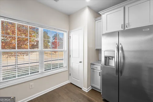 a view of a refrigerator in kitchen and an empty room