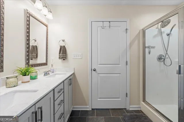 a bathroom with a double vanity sink mirror and shower