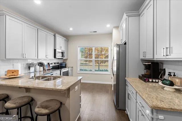 a kitchen with granite countertop a sink chairs and cabinets