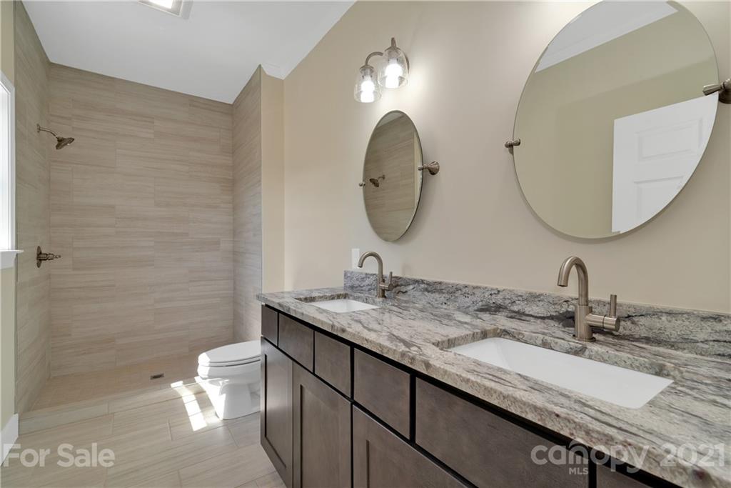 275 Ridge View Drive, Unit 1 Clyde, NC 28721 - Photo 14 of 22 a bathroom with a granite countertop sink a toilet and a mirror