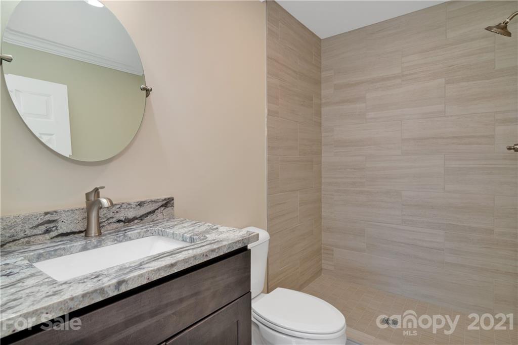 275 Ridge View Drive, Unit 1 Clyde, NC 28721 - Photo 18 of 22 a bathroom with a granite countertop sink a toilet and a mirror