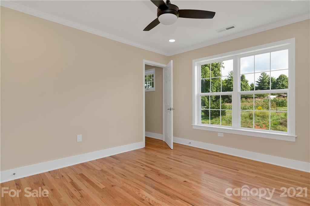 275 Ridge View Drive, Unit 1 Clyde, NC 28721 - Photo 19 of 22 an empty room with wooden floor ceiling fan and windows