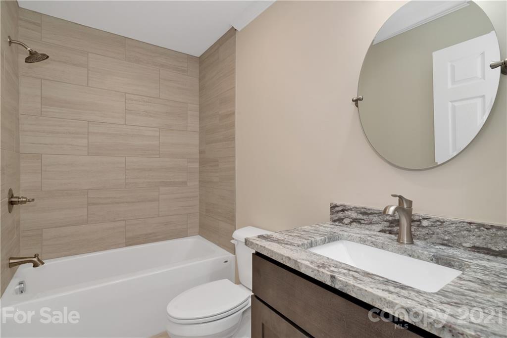 275 Ridge View Drive, Unit 1 Clyde, NC 28721 - Photo 21 of 22 a bathroom with a granite countertop sink a toilet and bathtub