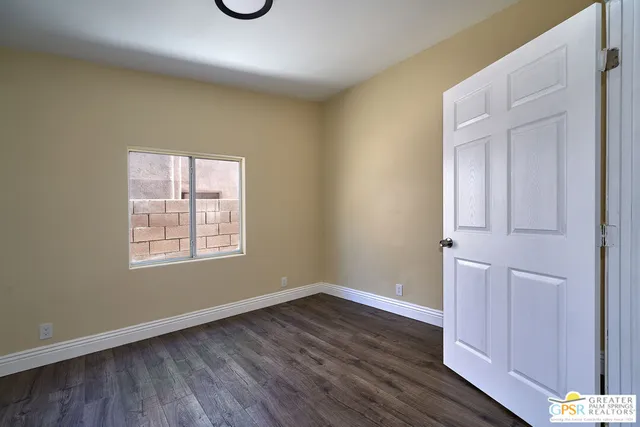 an empty room with wooden floor and window
