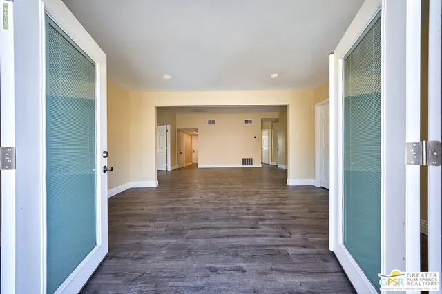 a view of an empty room with wooden floor and a bathroom
