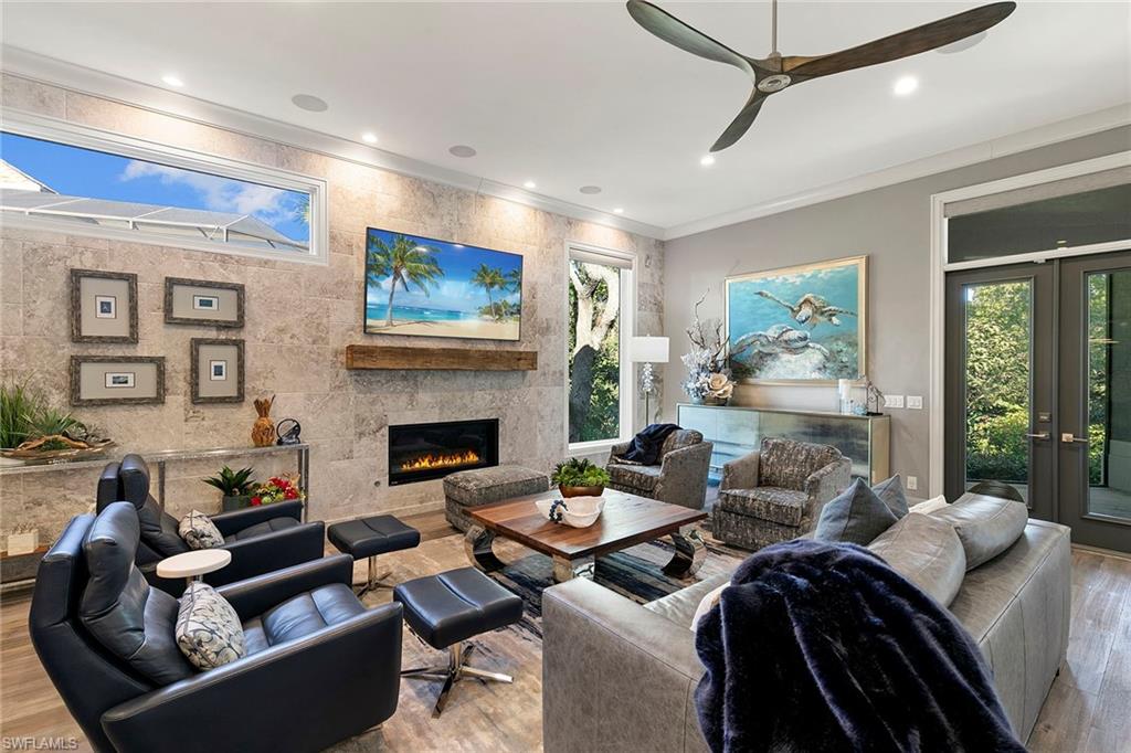927 Barcarmil Way Naples, FL 34110 - Photo 16 of 48 a living room with furniture a fireplace and a large window
