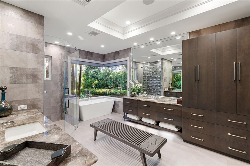 927 Barcarmil Way Naples, FL 34110 - Photo 22 of 50 Full bath with a stall shower, two vanities, a soaking tub, tile walls, and recessed lighting
