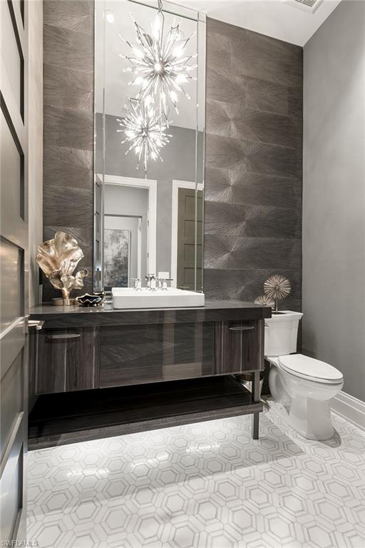 927 Barcarmil Way Naples, FL 34110 - Photo 28 of 50 Half bathroom featuring vanity and an accent wall