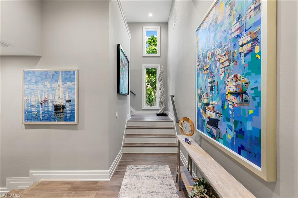 927 Barcarmil Way Naples, FL 34110 - Photo 32 of 50 Stairway featuring wood finished floors and a high ceiling