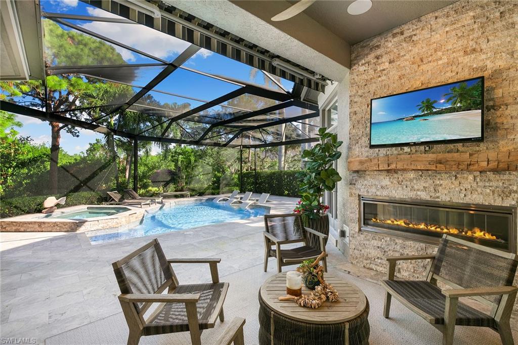 927 Barcarmil Way Naples, FL 34110 - Photo 39 of 50 Combined pool / hot tub with a sunroom, a patio, glass enclosure, and a glass covered fireplace