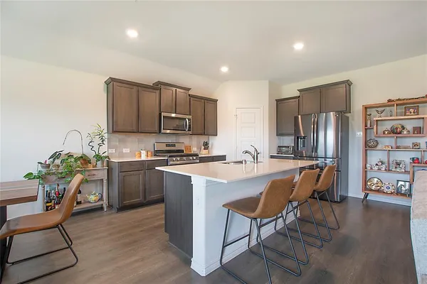 a kitchen with stainless steel appliances granite countertop a stove a refrigerator a sink dishwasher and a stove with wooden floor