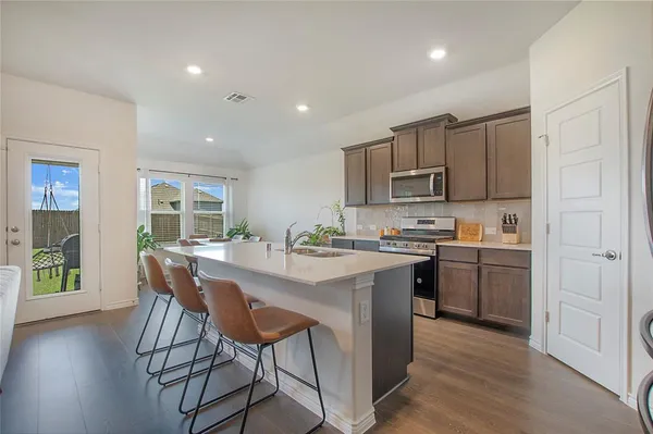 a kitchen with kitchen island granite countertop wooden floors and stainless steel appliances