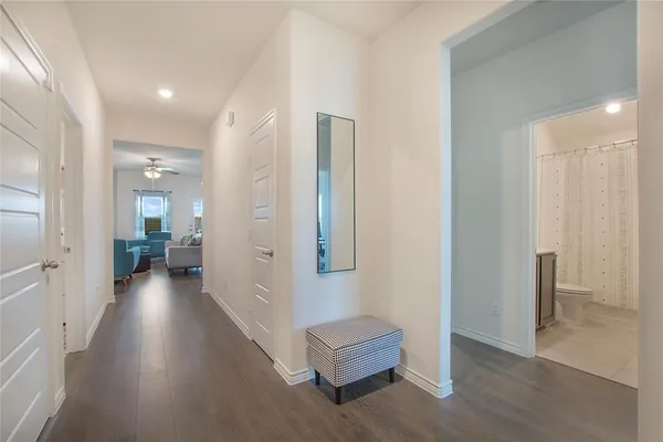 a view of a hallway with wooden floor and a bathroom
