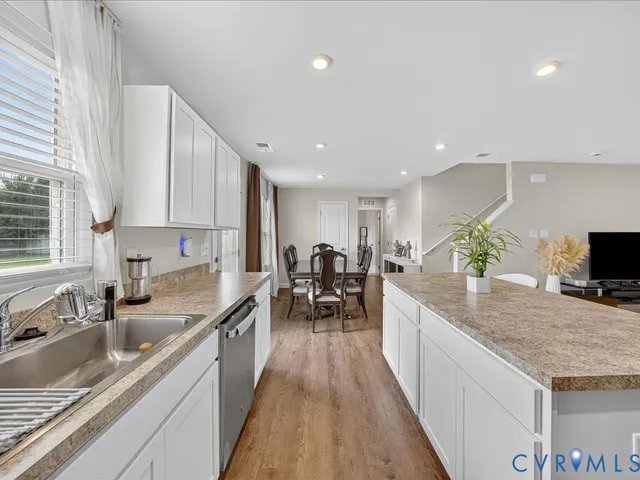 a large kitchen with granite countertop a large counter top stainless steel appliances a sink and living room view