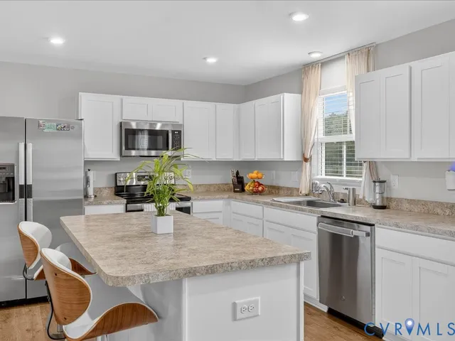 a kitchen with kitchen island granite countertop a sink stainless steel appliances and white cabinets