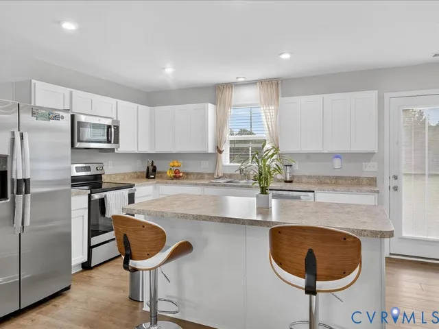 a kitchen with kitchen island granite countertop a sink cabinets and stainless steel appliances