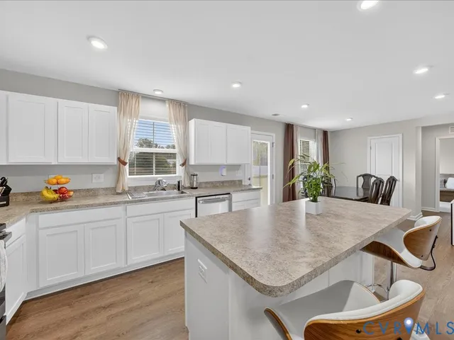 a kitchen with granite countertop kitchen island a sink a stove a counter space and cabinets