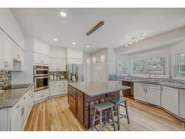a kitchen with stainless steel appliances granite countertop a stove refrigerator and a sink