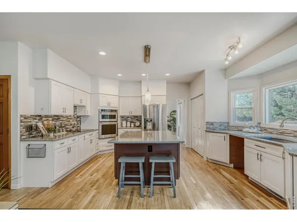 a kitchen with stainless steel appliances kitchen island granite countertop a stove and cabinets