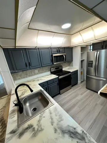 a kitchen with a sink a counter top space cabinets and stainless steel appliances
