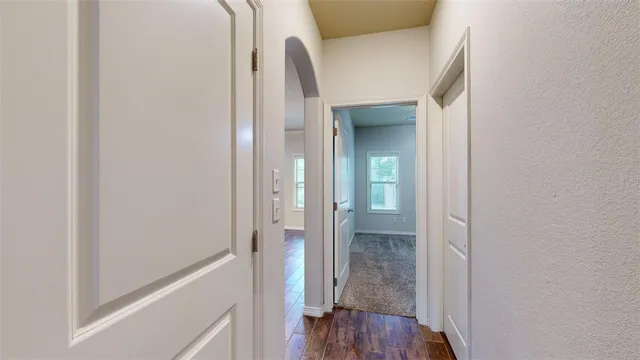 a view of a hallway with wooden floor and a livingroom